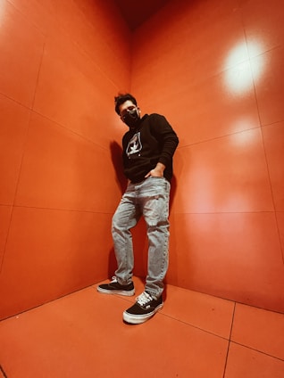 A close-up of a person wearing a sleek black nmsd concepts hoodie, standing confidently against an urban graffiti wall.