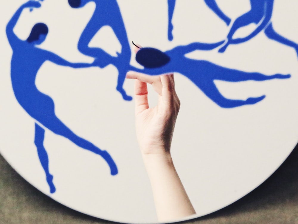 a person holding up a blue drawing on a white plate