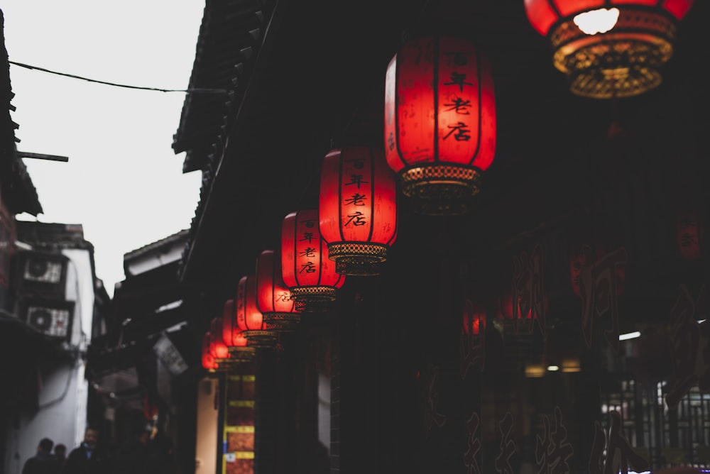 a group of red lanterns hanging from the side of a building