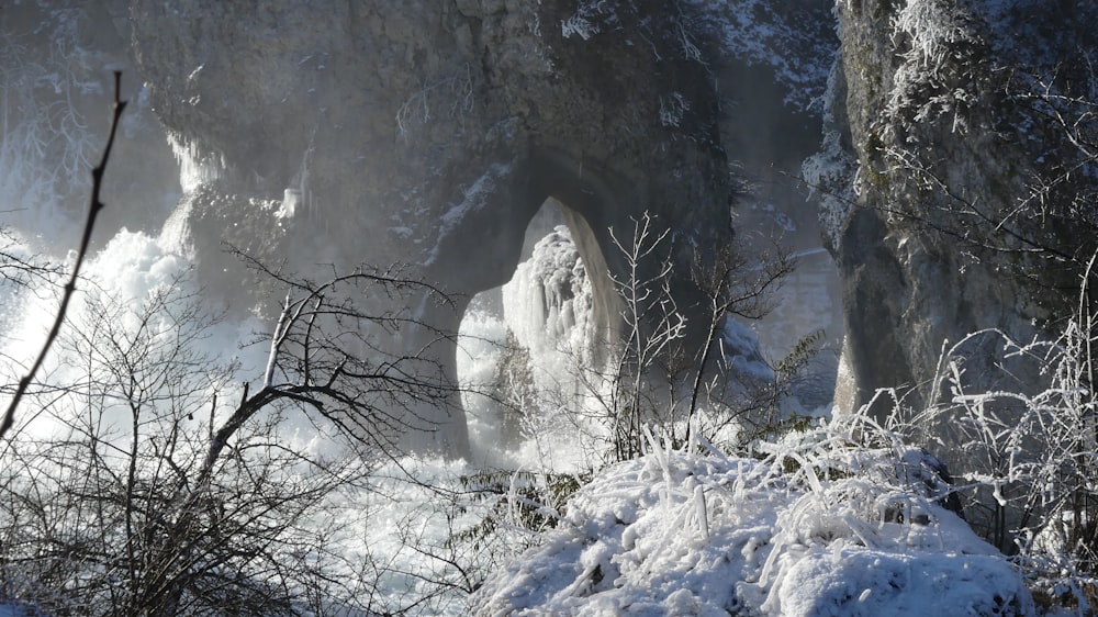 um penhasco coberto de neve com uma cachoeira no fundo