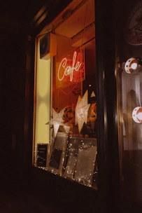 A cozy cafe window with a handwritten 'Now Featured' sign, sunlight streaming in.