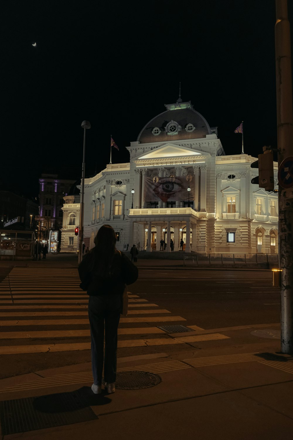 a woman taking a picture of a building at night