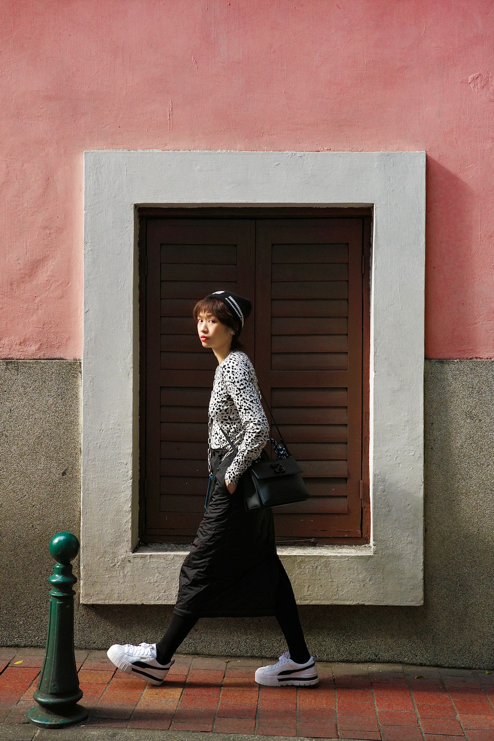 a woman walking down a sidewalk next to a building