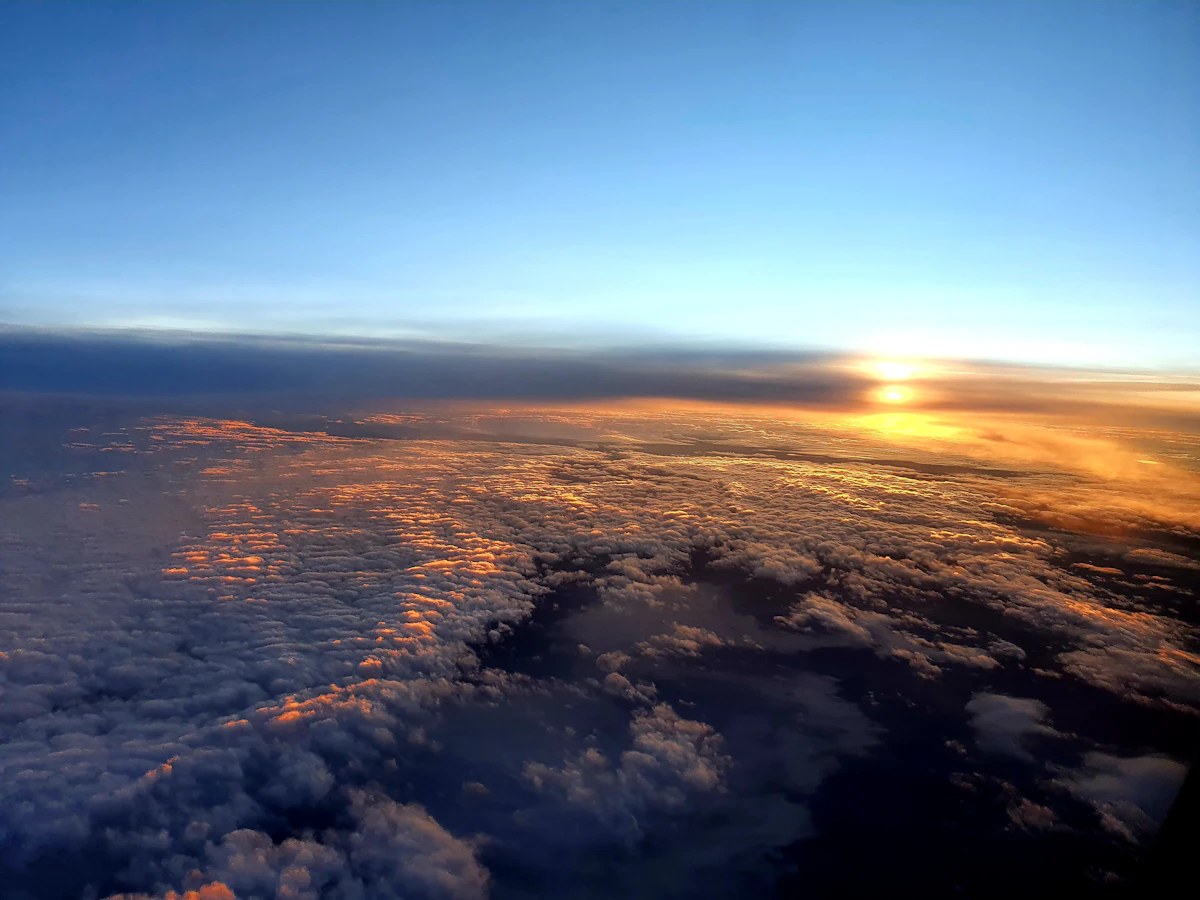 The sun setting over a thick layer of cloud, seen from an aircraft window
