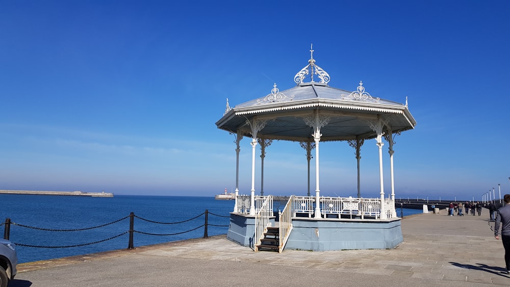 a gazebo sitting on top of a pier next to the ocean