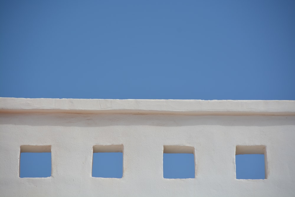 a white building with four windows and a sky background