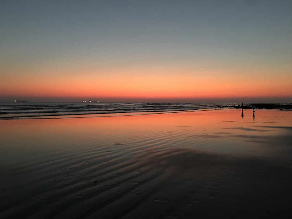 Eine Person, die bei Sonnenuntergang am Strand steht