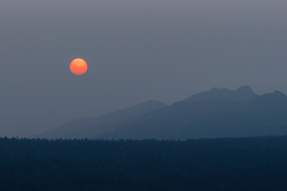 the sun is setting over a mountain range