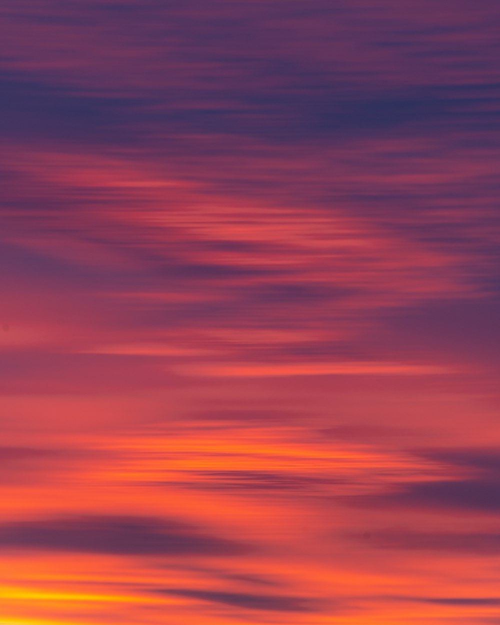 a plane flying in the sky at sunset