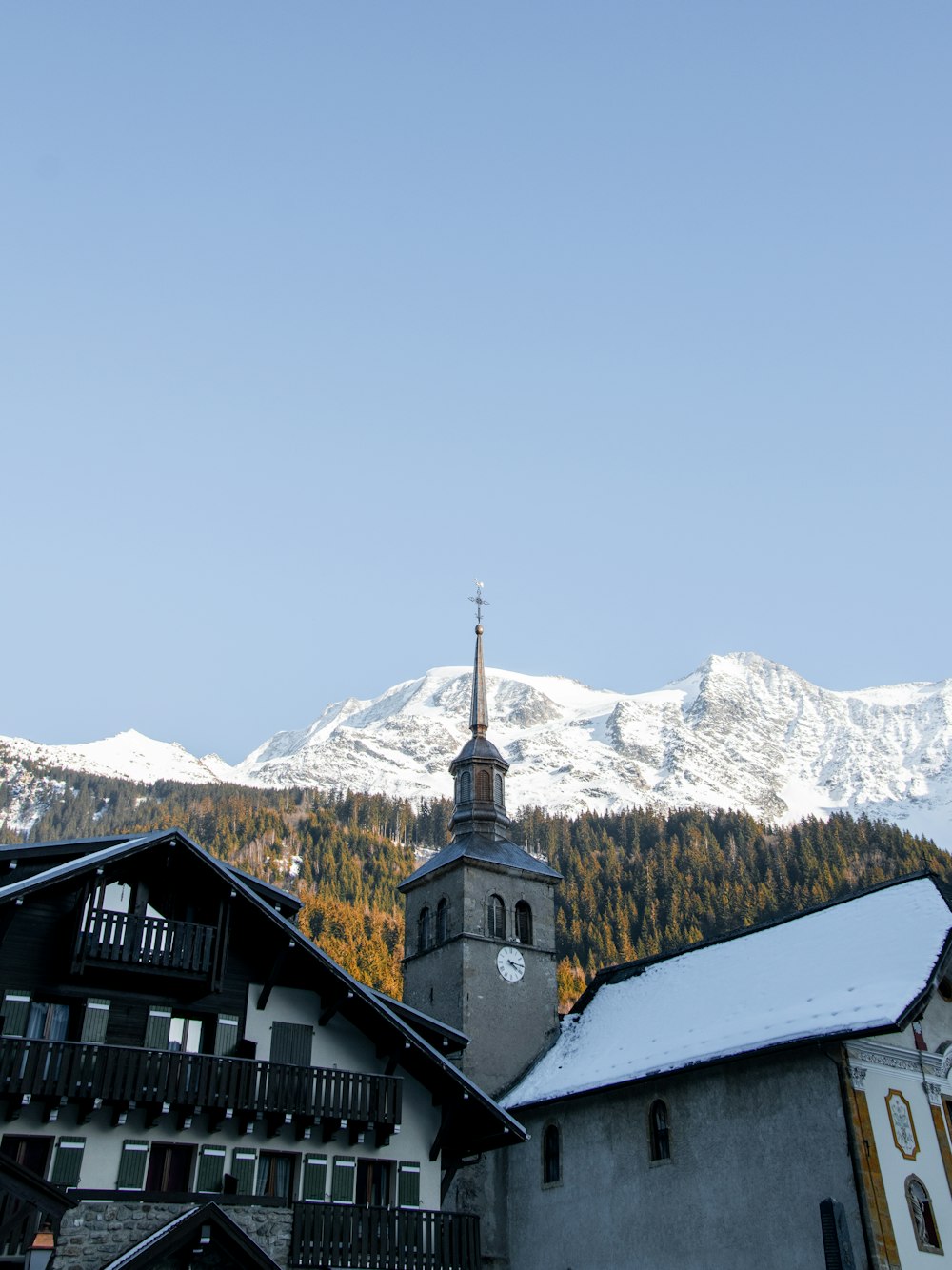 Ein Gebäude mit einem Kirchturm vor einem verschneiten Berg