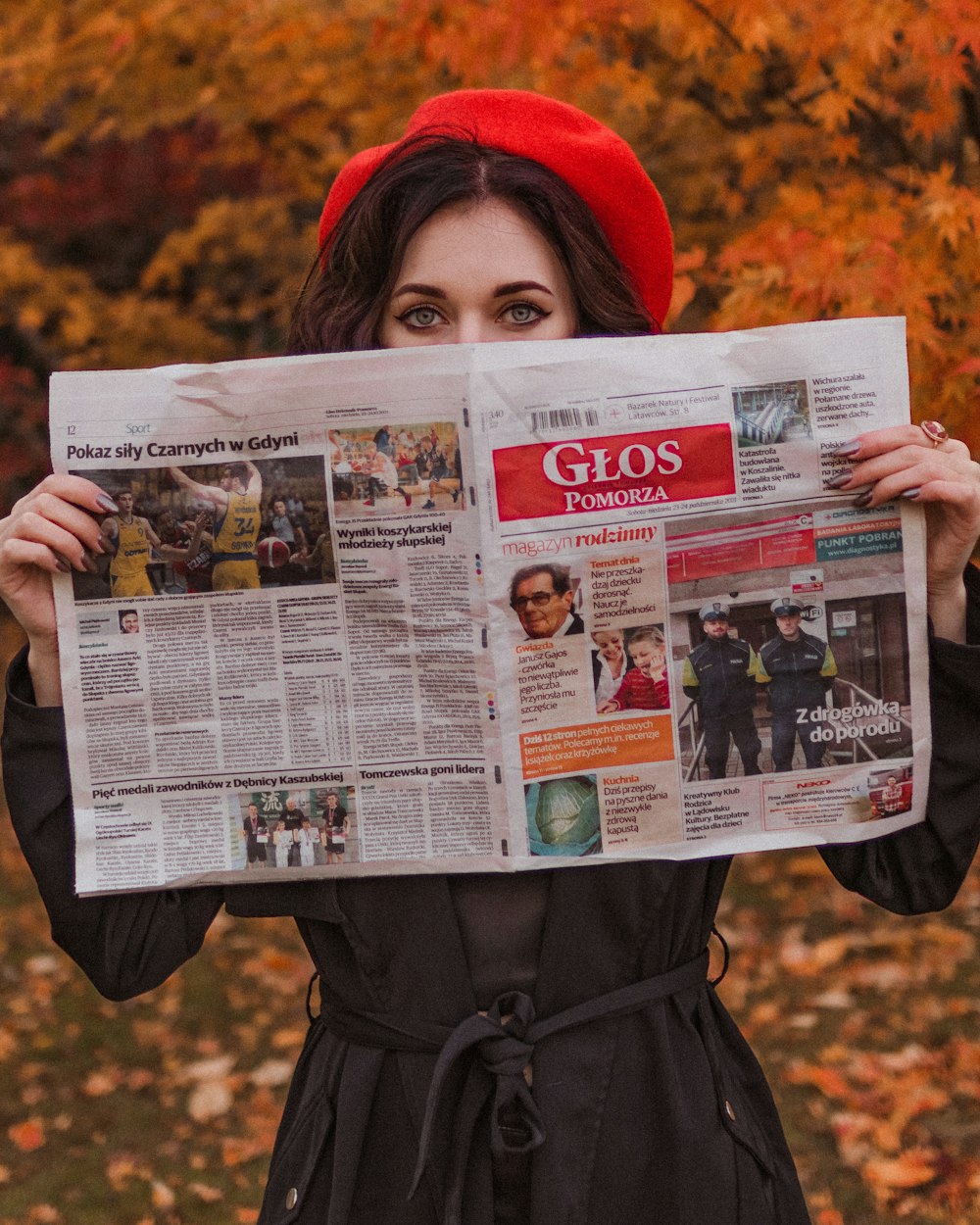 a woman in a red hat holding up a newspaper