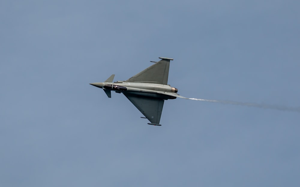 a fighter jet flying through a cloudy blue sky