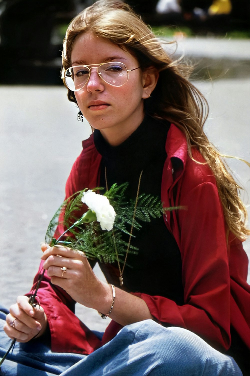 a woman sitting on the ground holding a flower