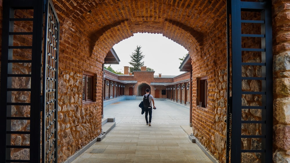 a woman is walking through a brick archway
