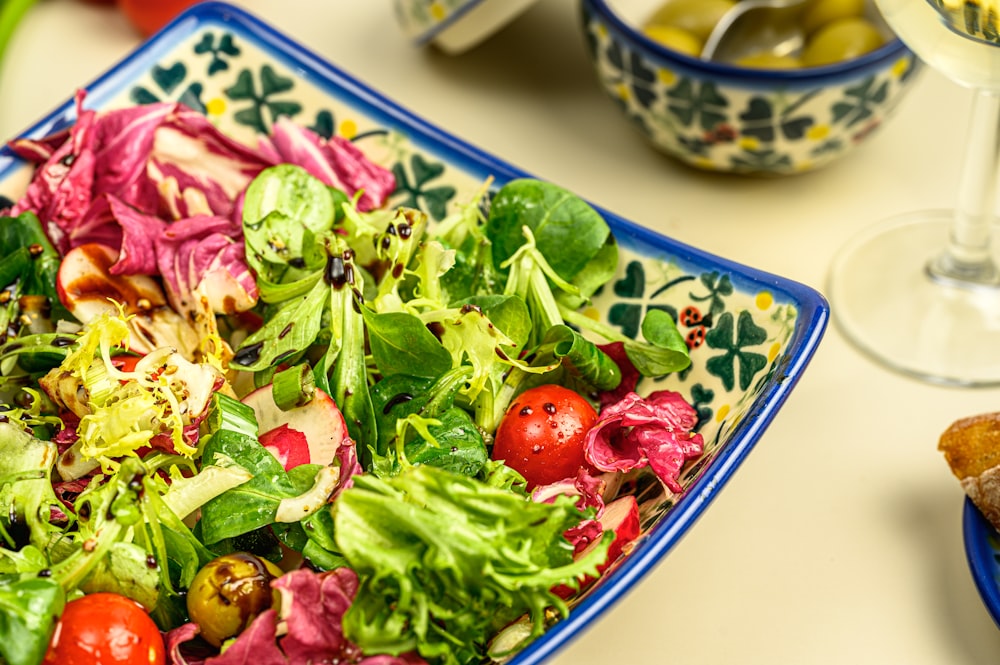 a plate of salad next to a glass of wine