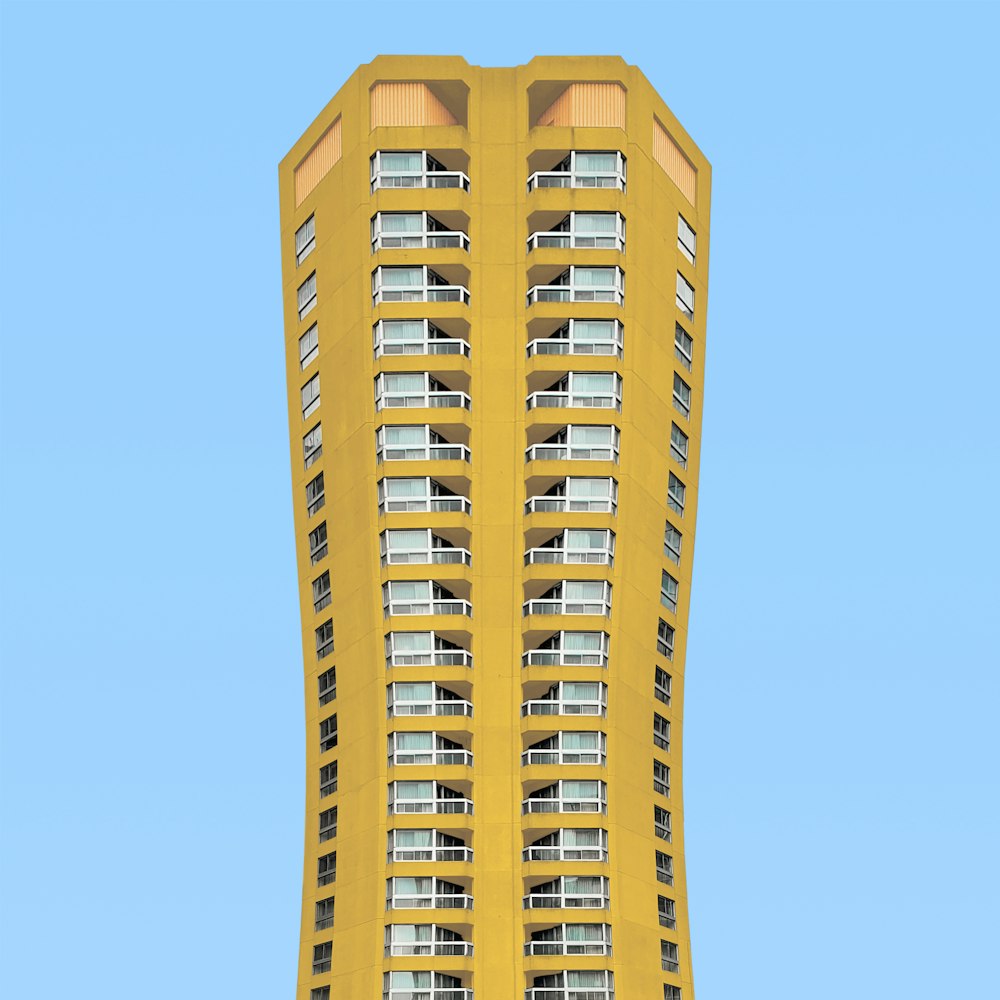 a tall yellow building with balconies on the windows