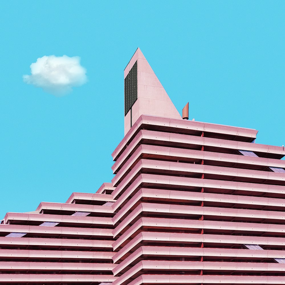 a pink building with a white cloud in the sky