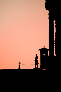 A vigilant security guard standing at the entrance of a commercial building during sunset.