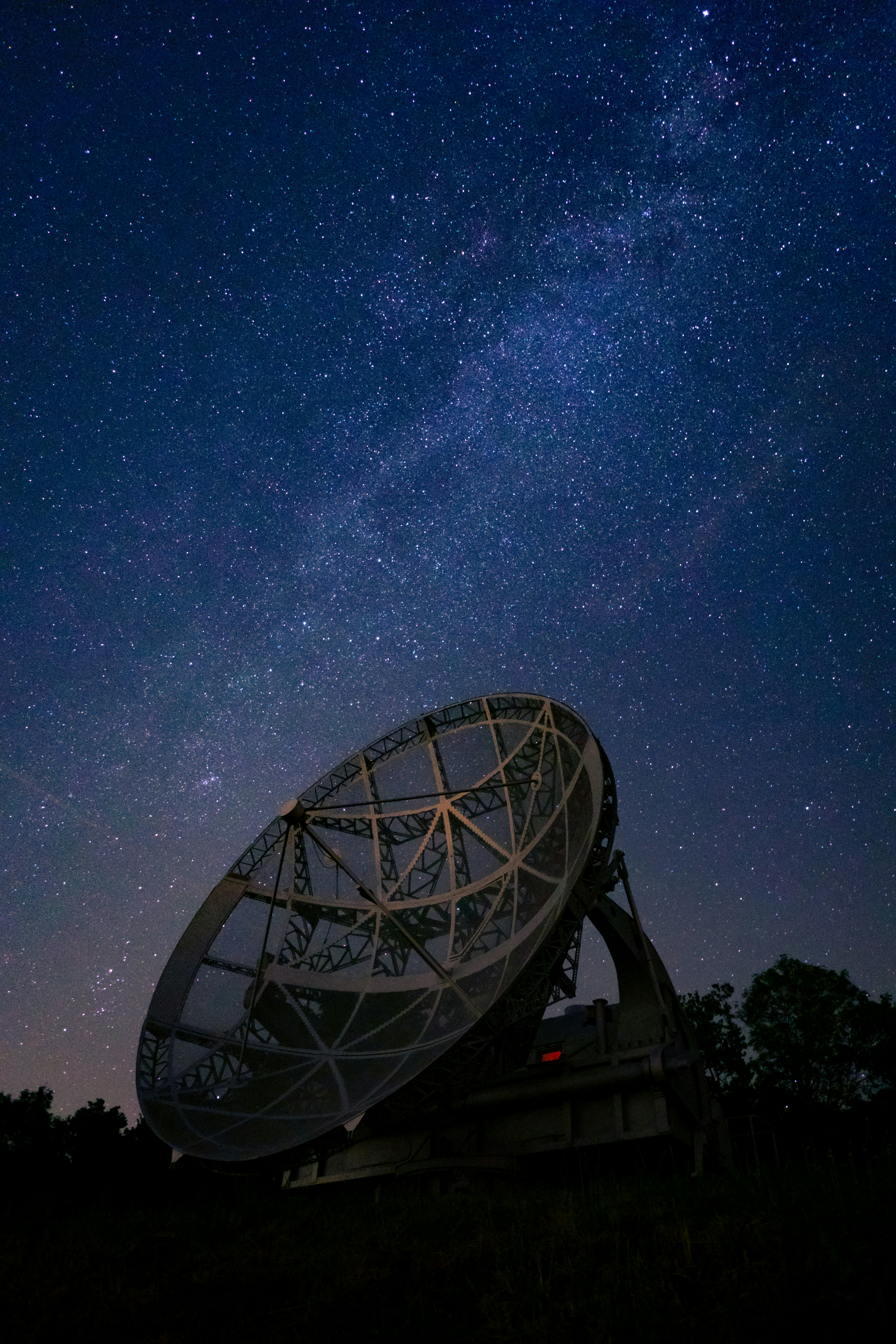 a satellite dish sitting on top of a hill under a night sky filled with stars