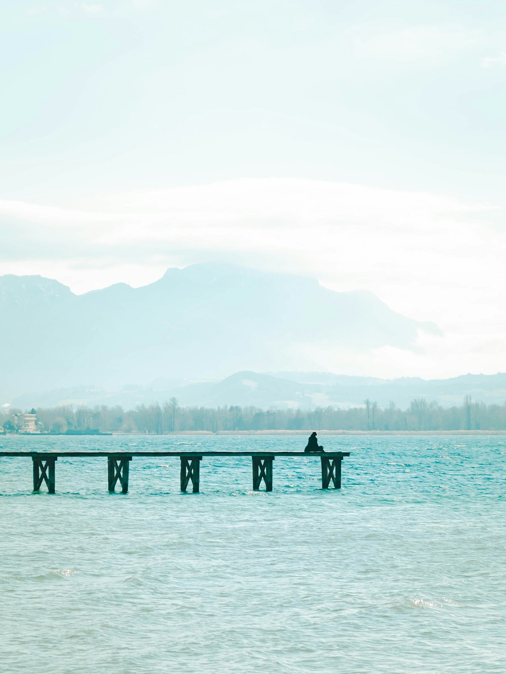 a person sitting on a pier in the middle of the ocean