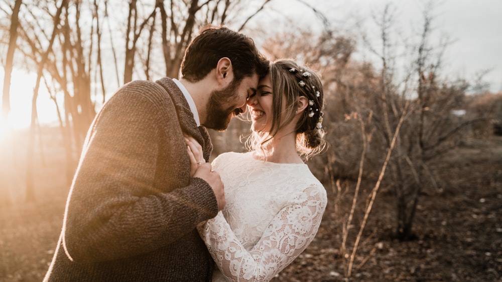 a bride and groom standing close together in the woods