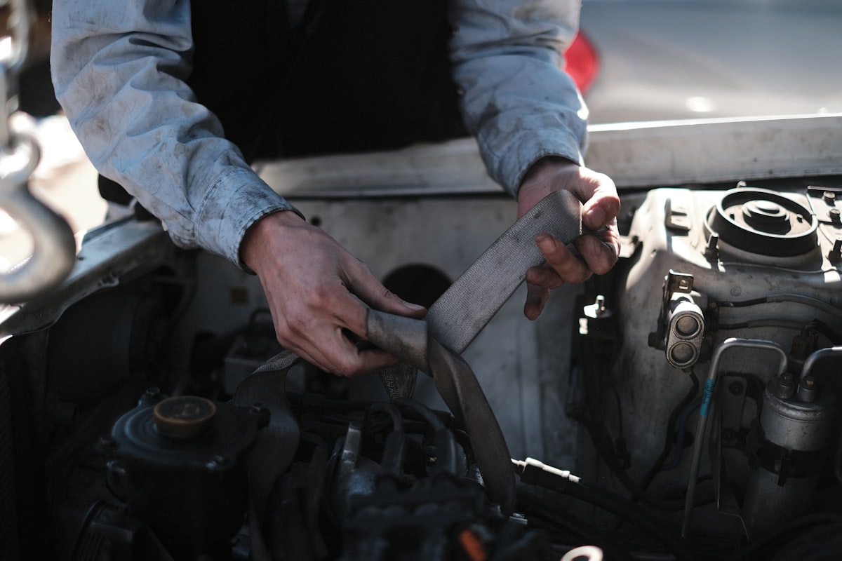 Professional mechanic working on car engine and battery system during winter preparation service