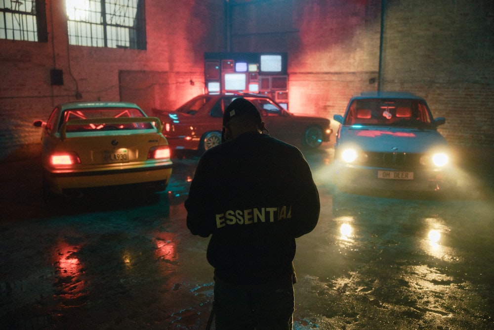a man standing in the rain next to a bunch of cars