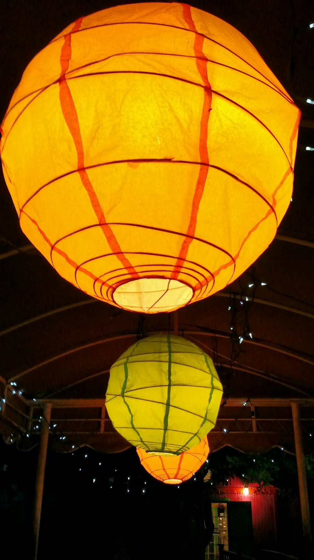 a couple of yellow lanterns hanging from a ceiling