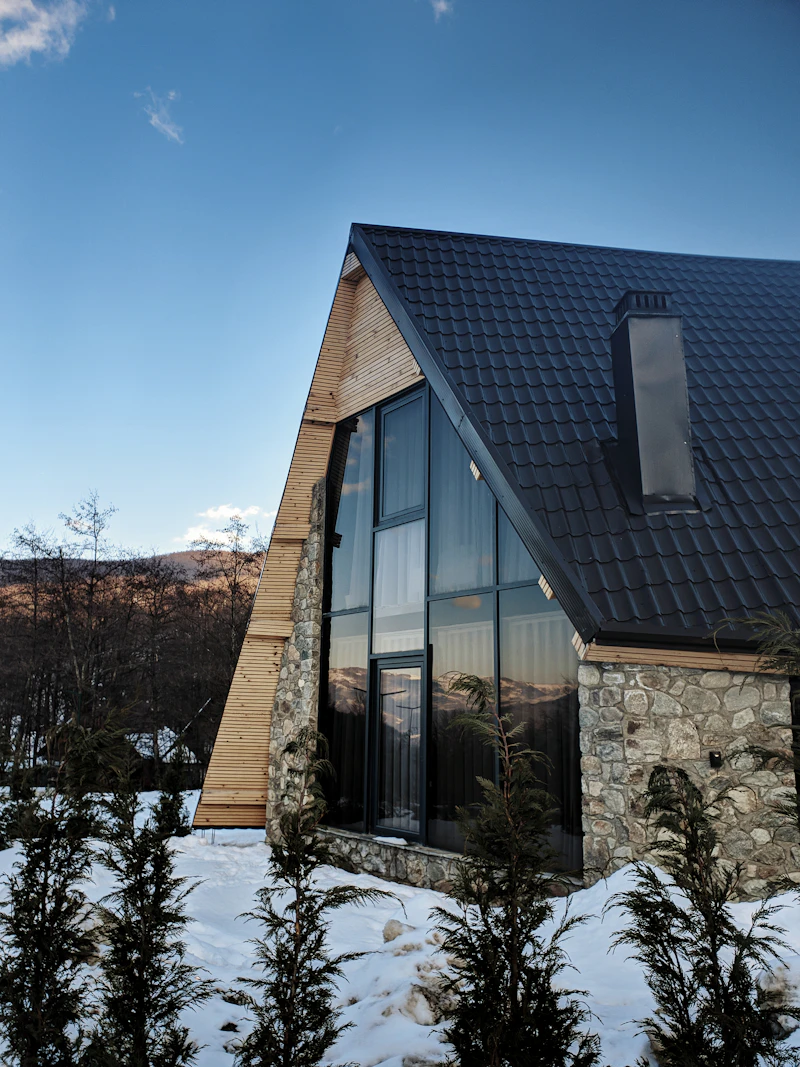 Stone house with black roof and windows
