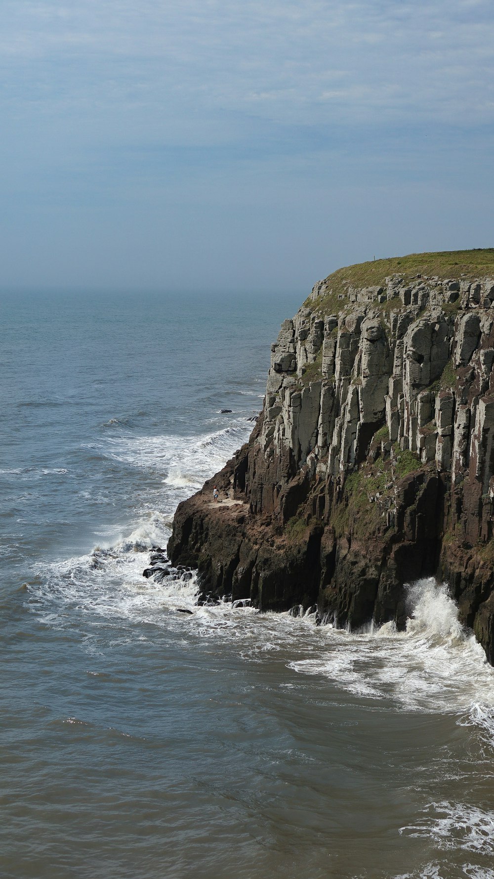 a rocky cliff next to a body of water