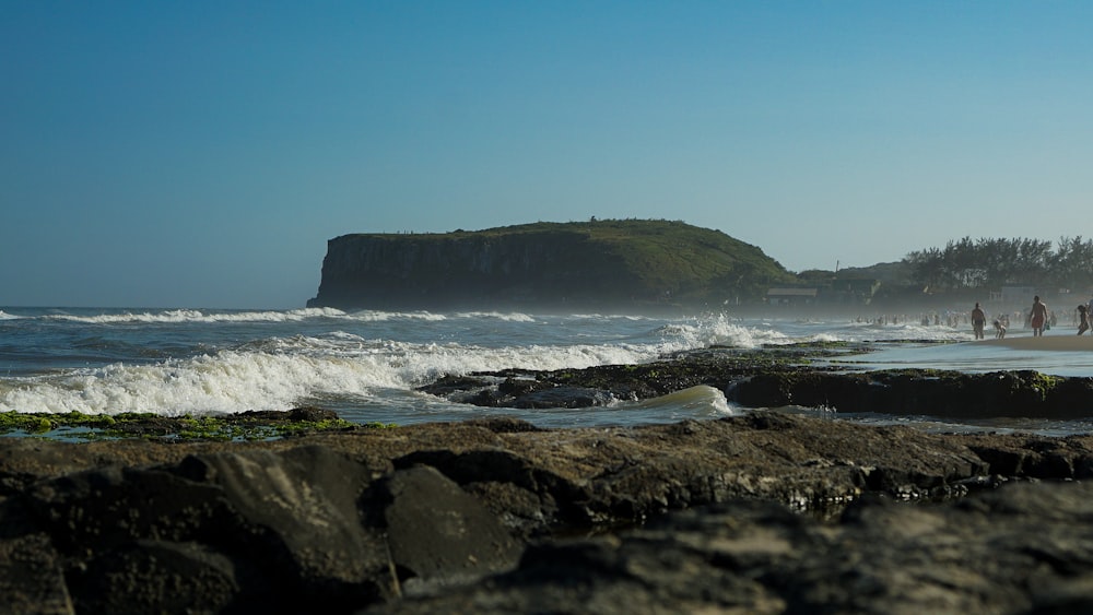 um grupo de pessoas em pé no topo de uma praia ao lado do oceano