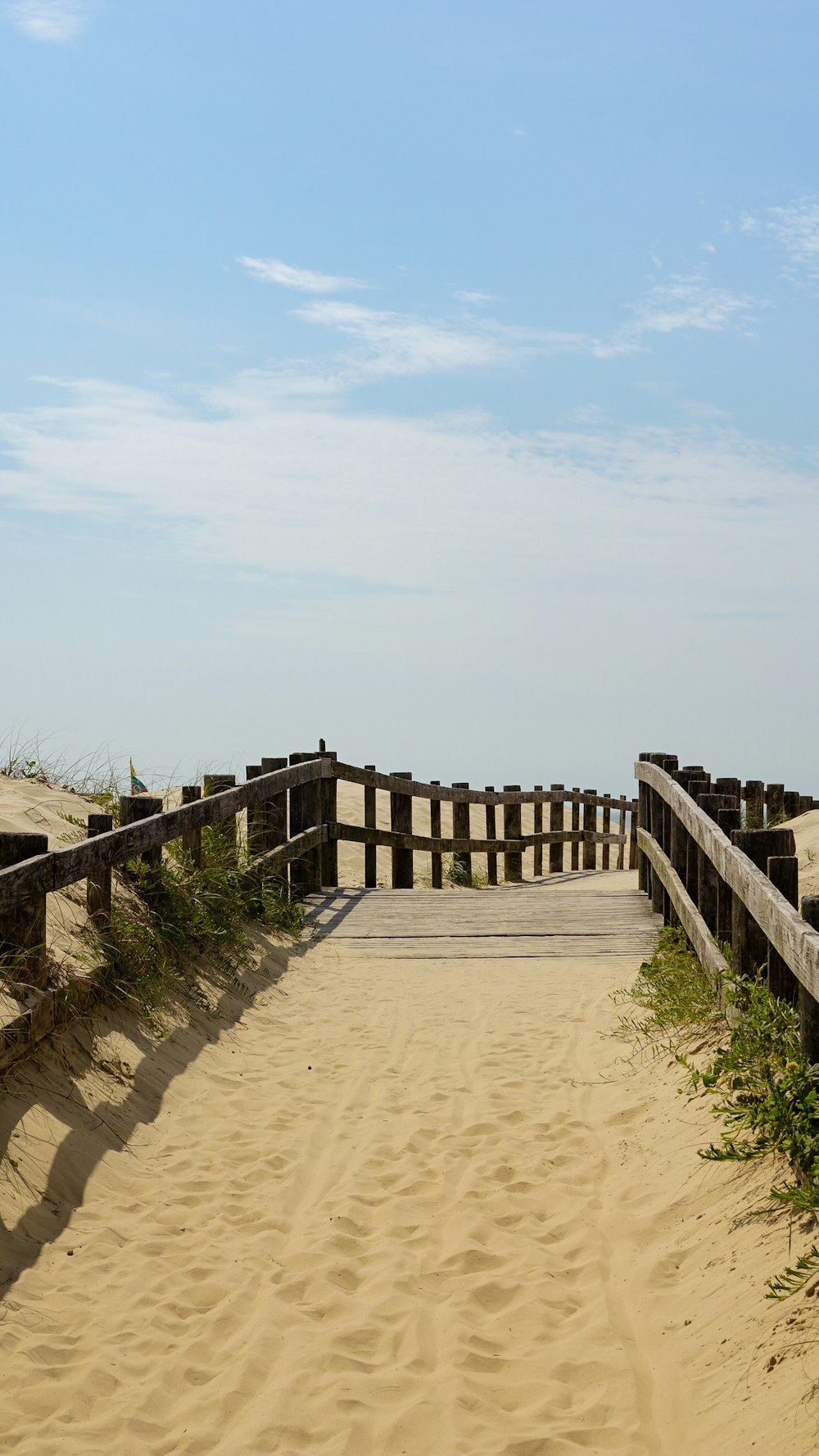 a wooden walkway leading to a sandy beach