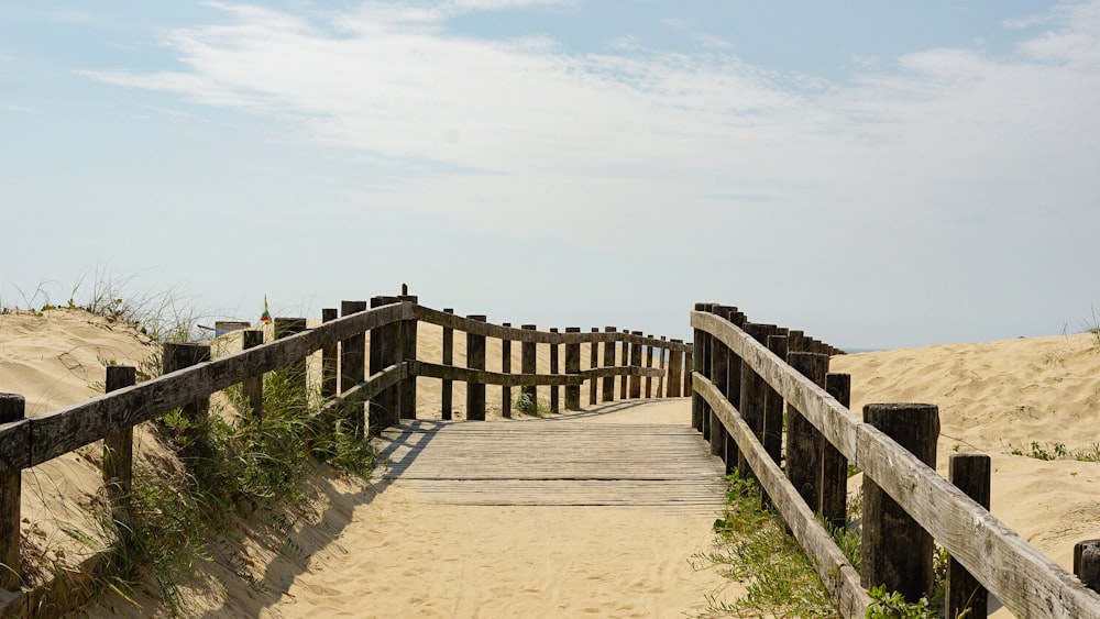 a wooden bridge over sand dunes leading to the beach