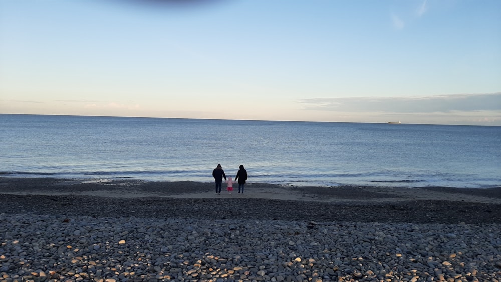 a couple of people standing on top of a beach