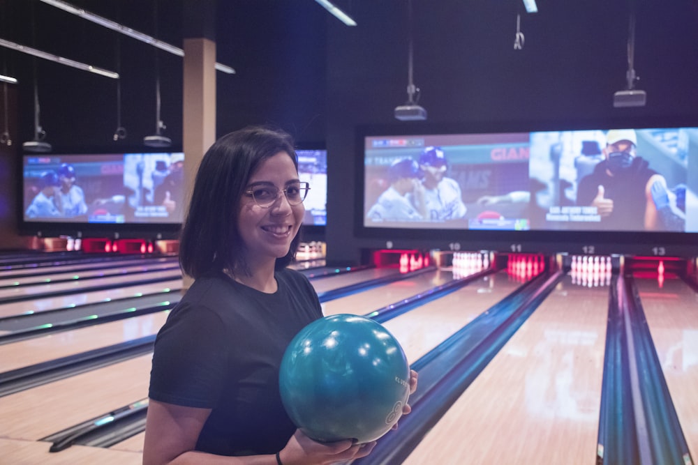 a woman holding a bowling ball in a bowling alley