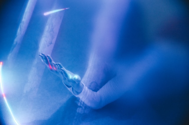 Close-up of a hand gently touching a glowing, ethereal aura surrounding the skin.