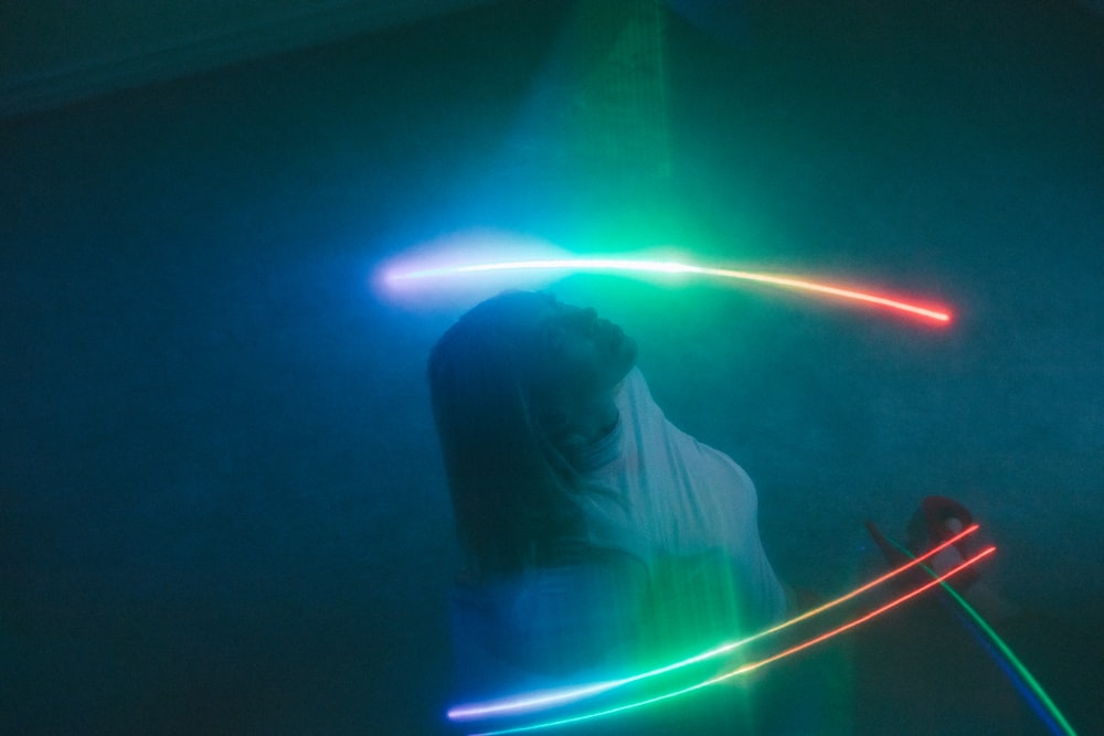 a woman standing in a dark room holding a light saber