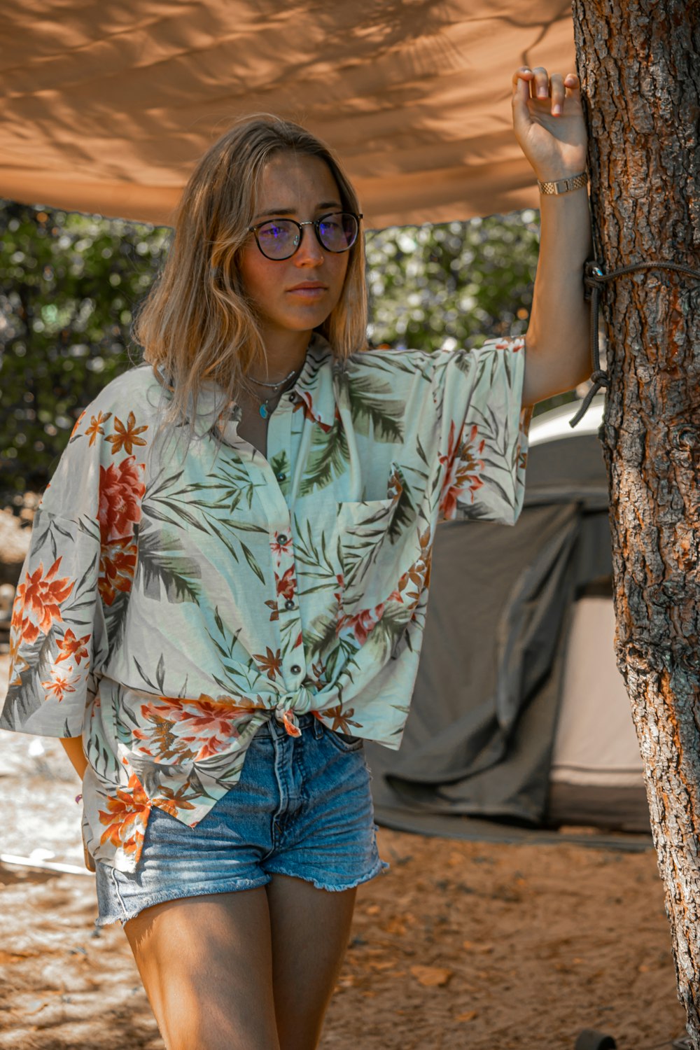 a woman standing next to a tree under a canopy