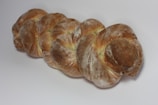 A loaf of bread with a braided shape, covered in a dusting of flour and displaying a golden-brown crust.