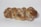 A loaf of braided bread with a golden-brown crust and a dusting of flour on its surface, placed on a plain white background.