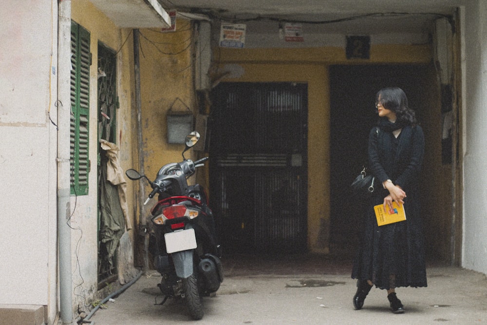a woman standing in front of a doorway with a moped