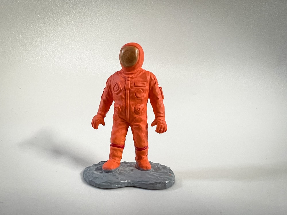 an orange astronaut figurine on a white background