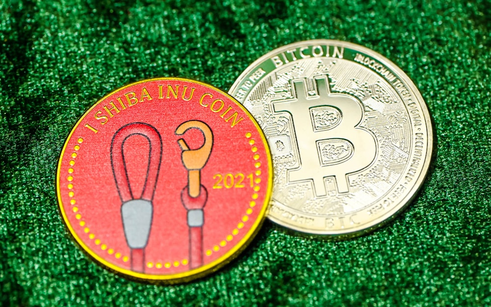 two bitcoins sitting side by side on a green surface