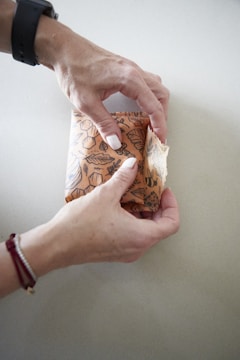 Close-up of hands wrapping a sofa with protective material.