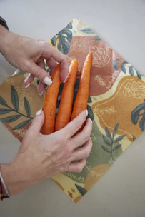 Close-up of hands holding fresh vegetables and a scientific report side by side.