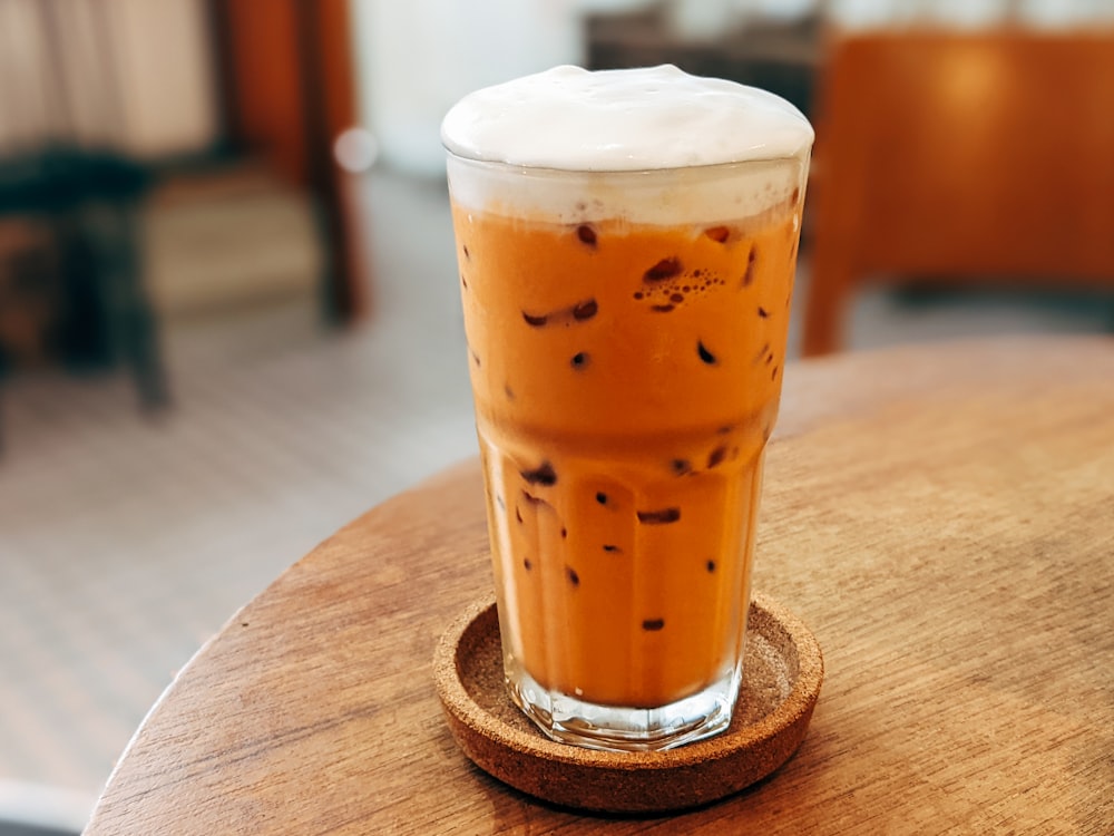 a glass of iced coffee sitting on top of a wooden table