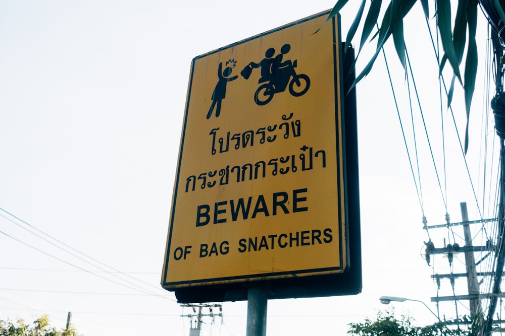 a yellow sign that says beware of bag snatchers