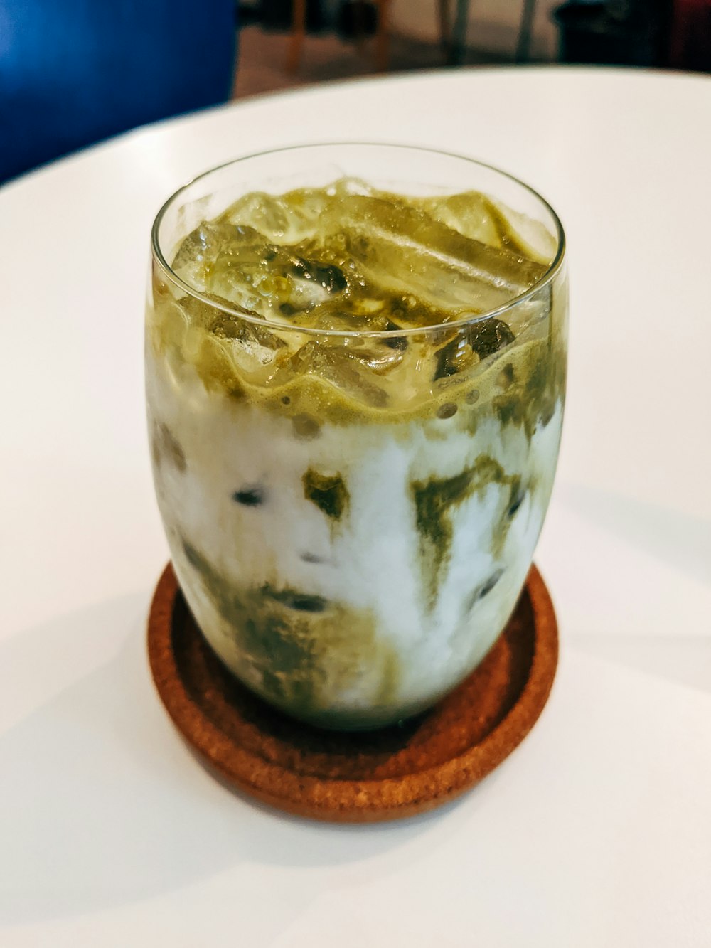 a glass of ice cream with a wooden coaster on a table