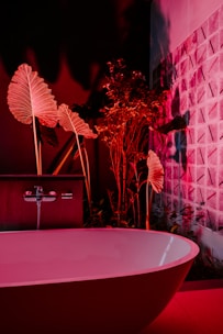 a bathroom with a pink bathtub and a plant