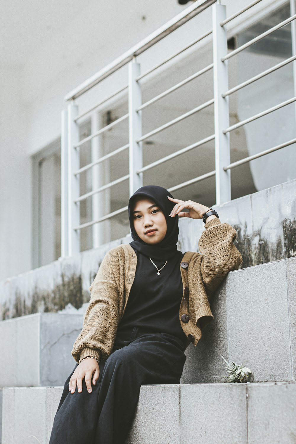 a woman sitting on a ledge wearing a hijab